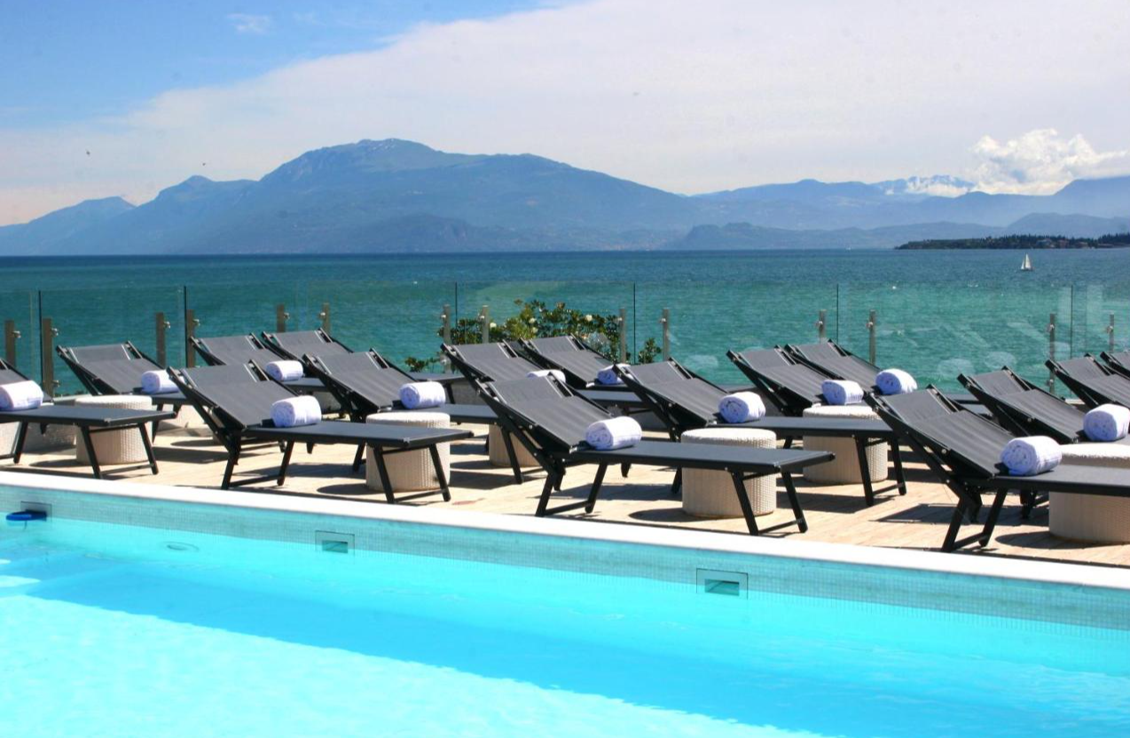 Zwembad en ligbedden met uitzicht van Park Hotel Gardameer