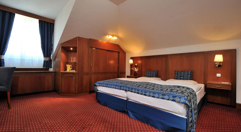 Slaapkamer met tweepersoonsbed van hotel Carlton Budapest