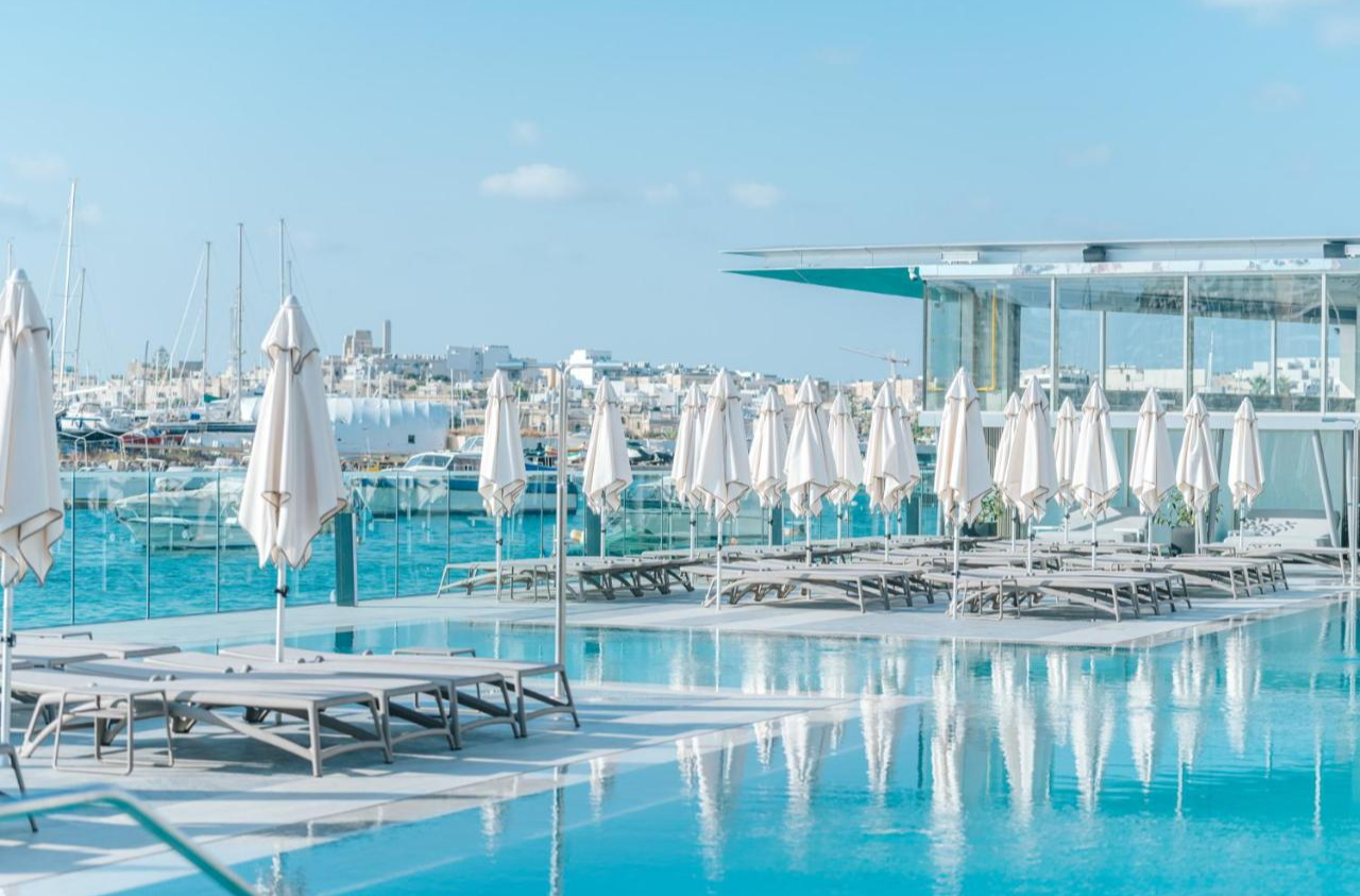 Zwembad en ligbedden van Hotel & Suites 115 The Strand Malta